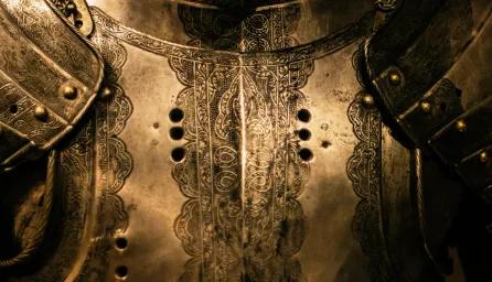 A close-up of a suit of armour in a darkly lit room. 