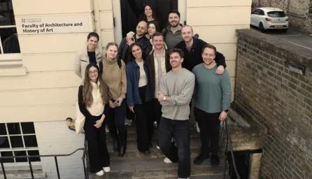 A group of apprentices standing on the steps outside a University of Cambridge faculty building.