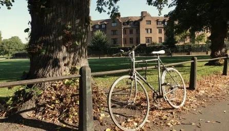 Bicycle leaning against railings by a lawn in front of a college