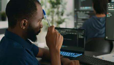 Man working in an office looking at two computer screens