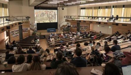 A view from the top of a large lecture theatre full of students. 