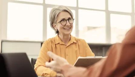 Lady holding notes smiling at person opposite her