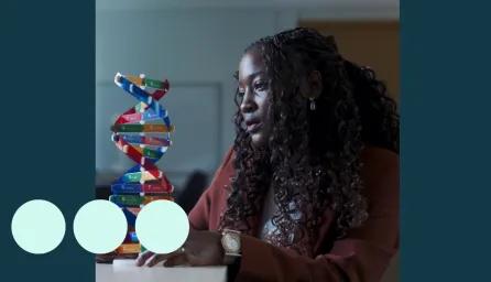Black woman, sat analysing a DNA model 