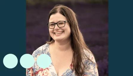woman with long brown hair and glasses smiling for photo 