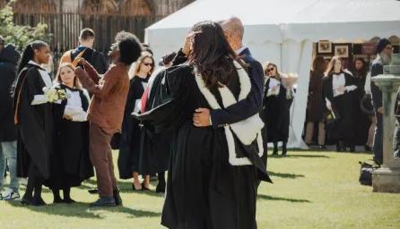 A graduate and guest posing for a photo on graduation day