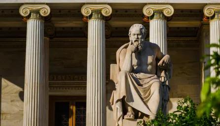 Statue of a philosopher outside a building with columns