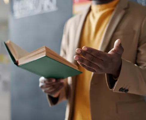 Person reading from a book and gesturing