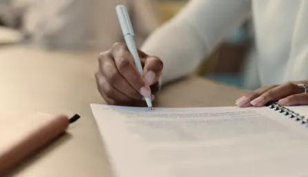 Person sitting at a desk writing a report