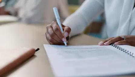 Person sitting at a desk writing a report