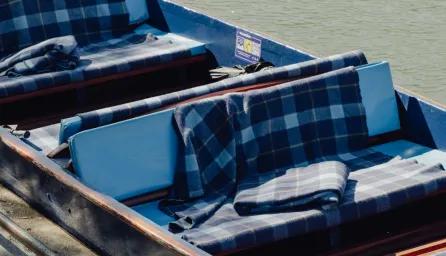 A punt with tartan blankets on the river cam.