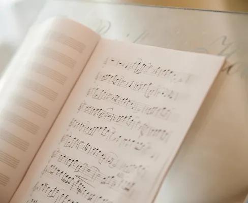 An open book of sheet music on a stand, showing pages filled with musical notes