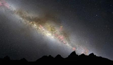 A silhouette of mountains beneath a starry night sky, with subtle colours of the galaxy visible among the stars.