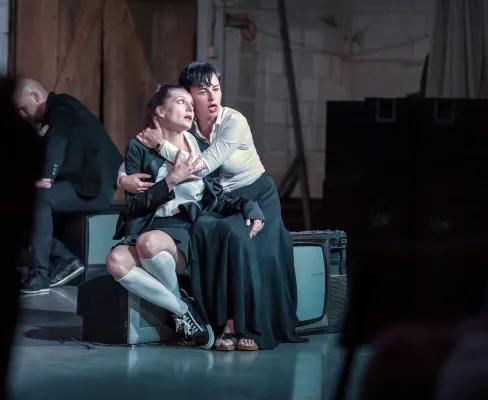 Two actors on a stage embracing