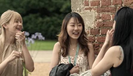 3 girls laughing in conversation at a garden party 