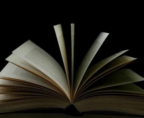 An open book with its pages fanned out against a black background