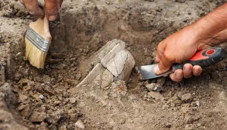 Archaeological excavations, archaeologists work, dig up an ancient clay artifact with special tools in soil.