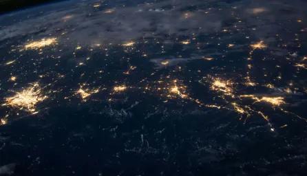 Satellite view of the world at night, with different cities and towns illuminated.