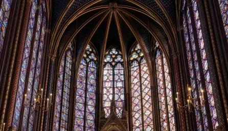 Multicoloured tall stained glass windows viewed from the inside of Sainte Chapelle looking up towards the ceiling.