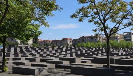 Holocaust Memorial in Berlin, Germany, with trees and clear sky.