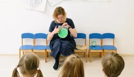 Teacher engages children during storytime in a colourful preschool classroom
