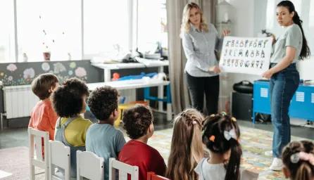 Teachers engage children in learning alphabet during a kindergarten class