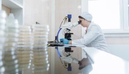 Female scientist using a microscope in a laboratory environment, focusing on research.