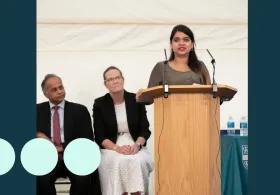 woman stood at podium delivery a speech
