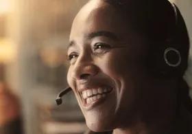 A smiling woman wearing a headset.