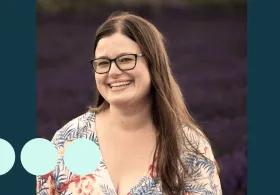 woman with long brown hair and glasses smiling for photo 