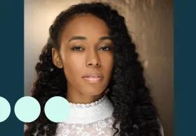 Headshot of woman with thick black curly hair, looking directly into camera