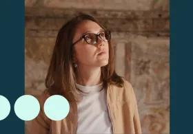 Woman with glasses looking up at tapestry 