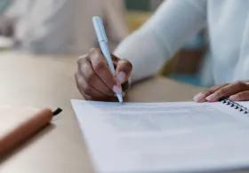 Person sitting at a desk writing a report