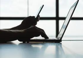 Student logging into a laptop with phone