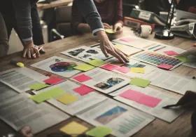 Various papers and post-it notes on table with people leaning in