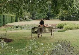 A student relaxing in Newnham College gardens.