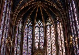 Multicoloured tall stained glass windows viewed from the inside of Sainte Chapelle looking up towards the ceiling.