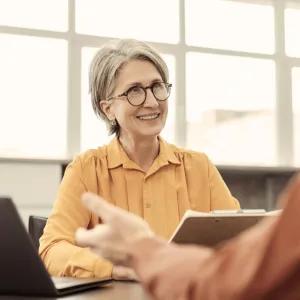 Lady holding notes smiling at person opposite her