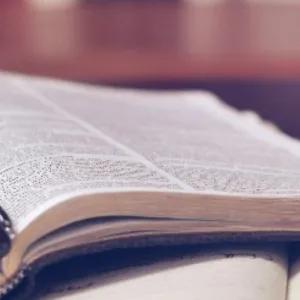 Open philosophical book with a pen resting in the center, pages slightly curved, and a softly blurred background.