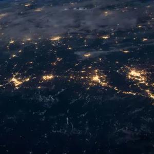 Satellite view of the world at night, with different cities and towns illuminated.