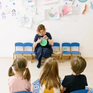 Teacher engages children during storytime in a colourful preschool classroom