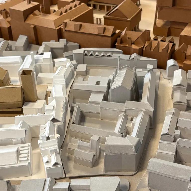 A close-up of an architectural model of an urban or town layout in white, grey and brown shot from above.