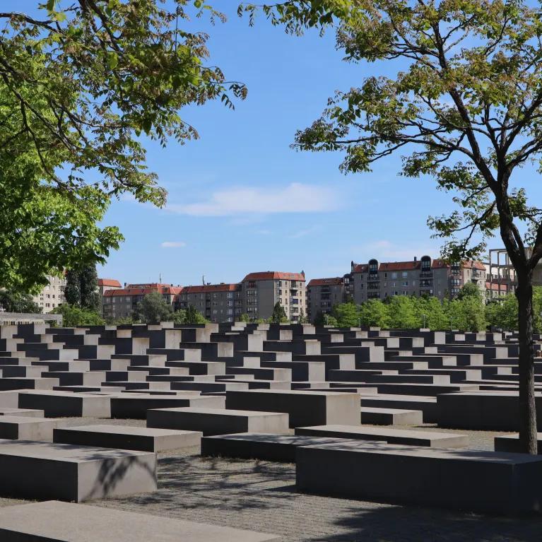 Holocaust Memorial in Berlin, Germany, with trees and clear sky.