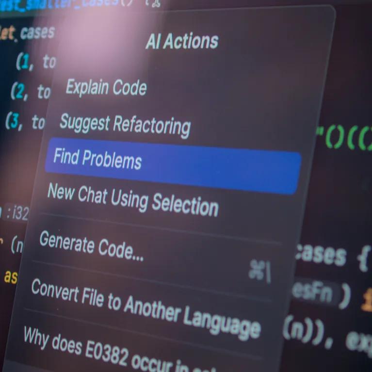 Close up of a computer screen displaying multicoloured computer code, and a pop-up box with AI options for actions.