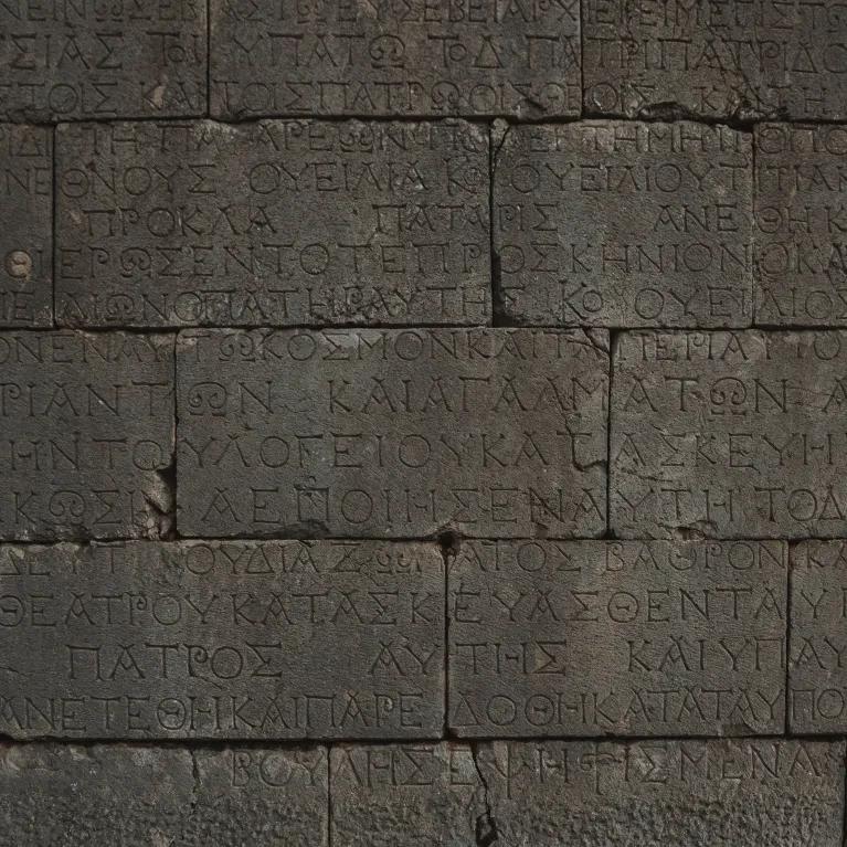 Close-up of an ancient stone wall with Greek inscriptions engraved on it