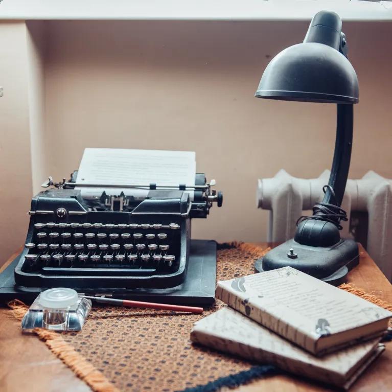 Typewriter, books, and a table lamp