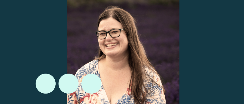 woman with long brown hair and glasses smiling for photo 
